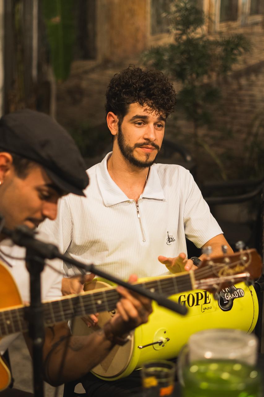 Dois músicos do grupo, um no banjo e outro no surdo amarelo com o adesivo Fala Garoto